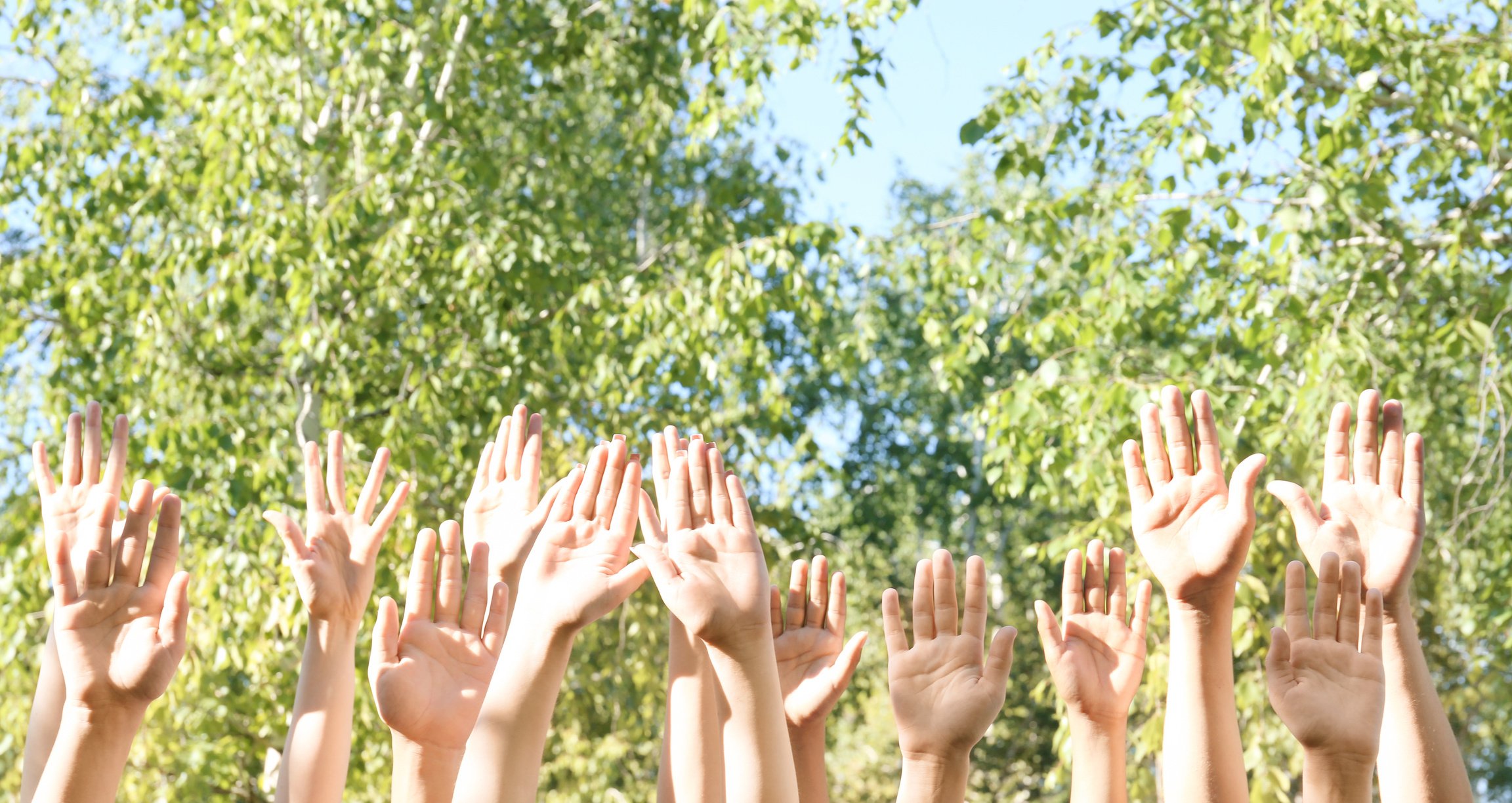 Young People Putting Hands in Air Together Outdoors